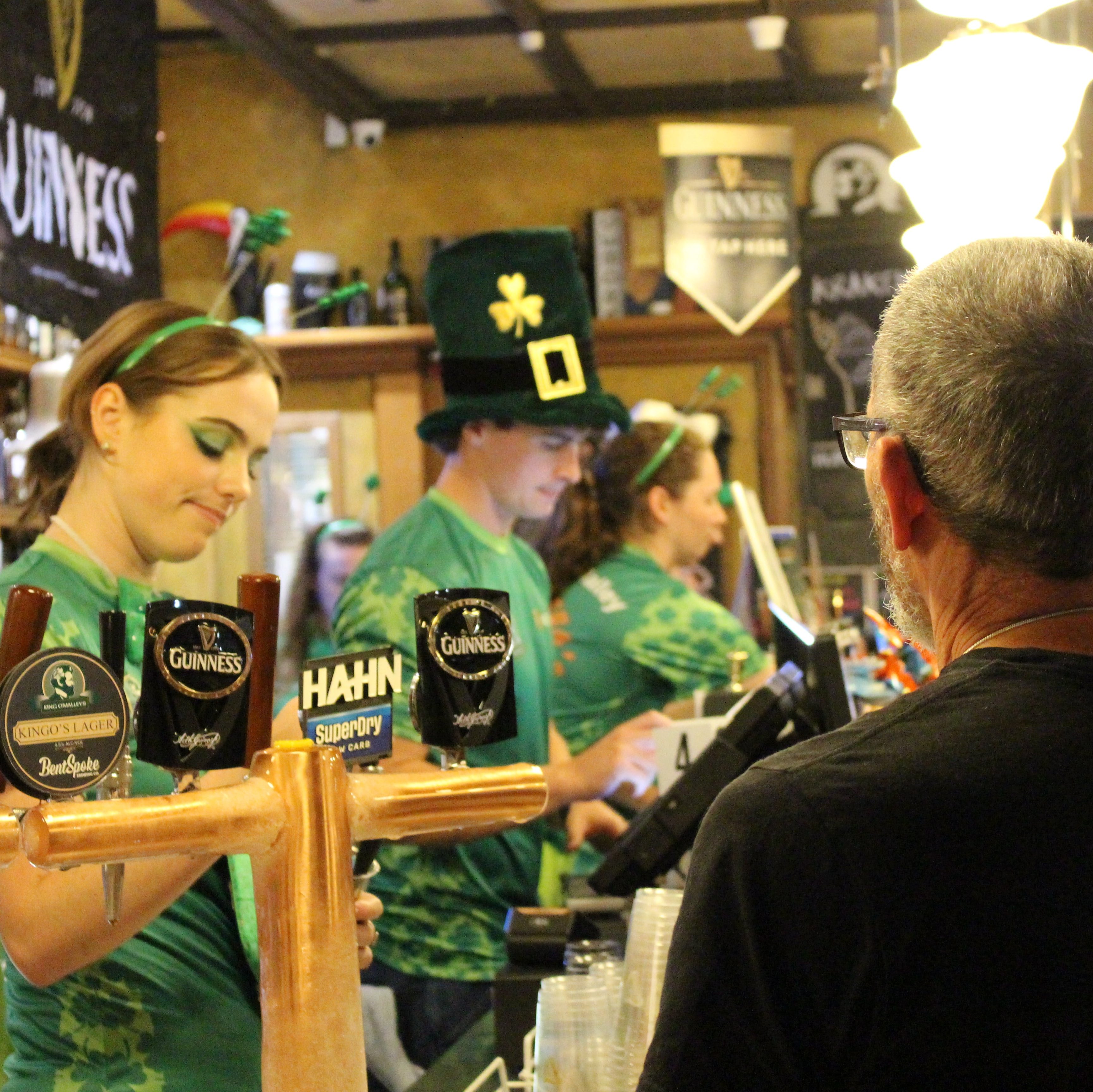 Bartenders dressed in St Patrick's Day themed outfits pour drinks for the waiting patrons