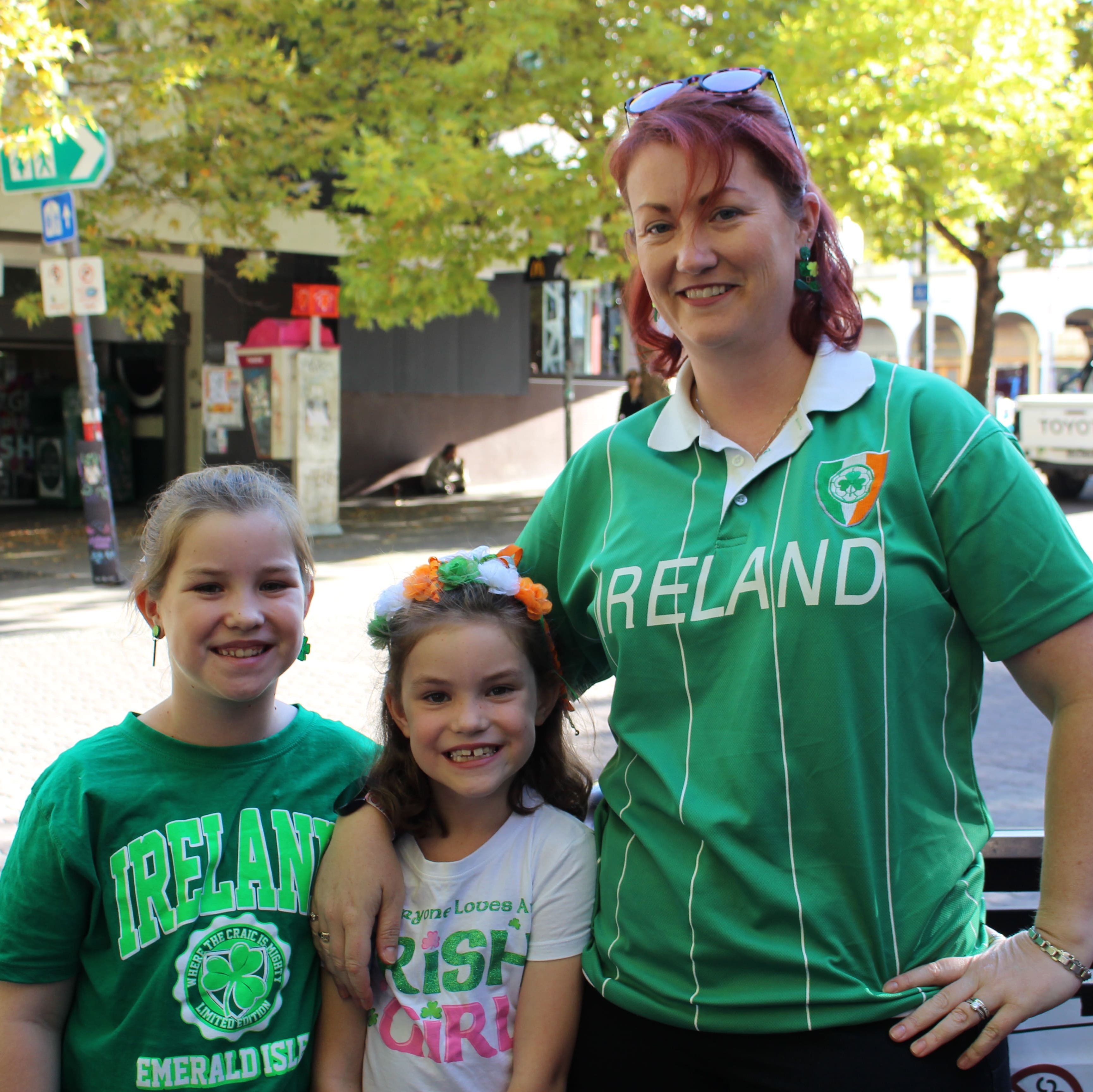 A mother and her two daughters pose together whilst wearing Irish themed clothing.