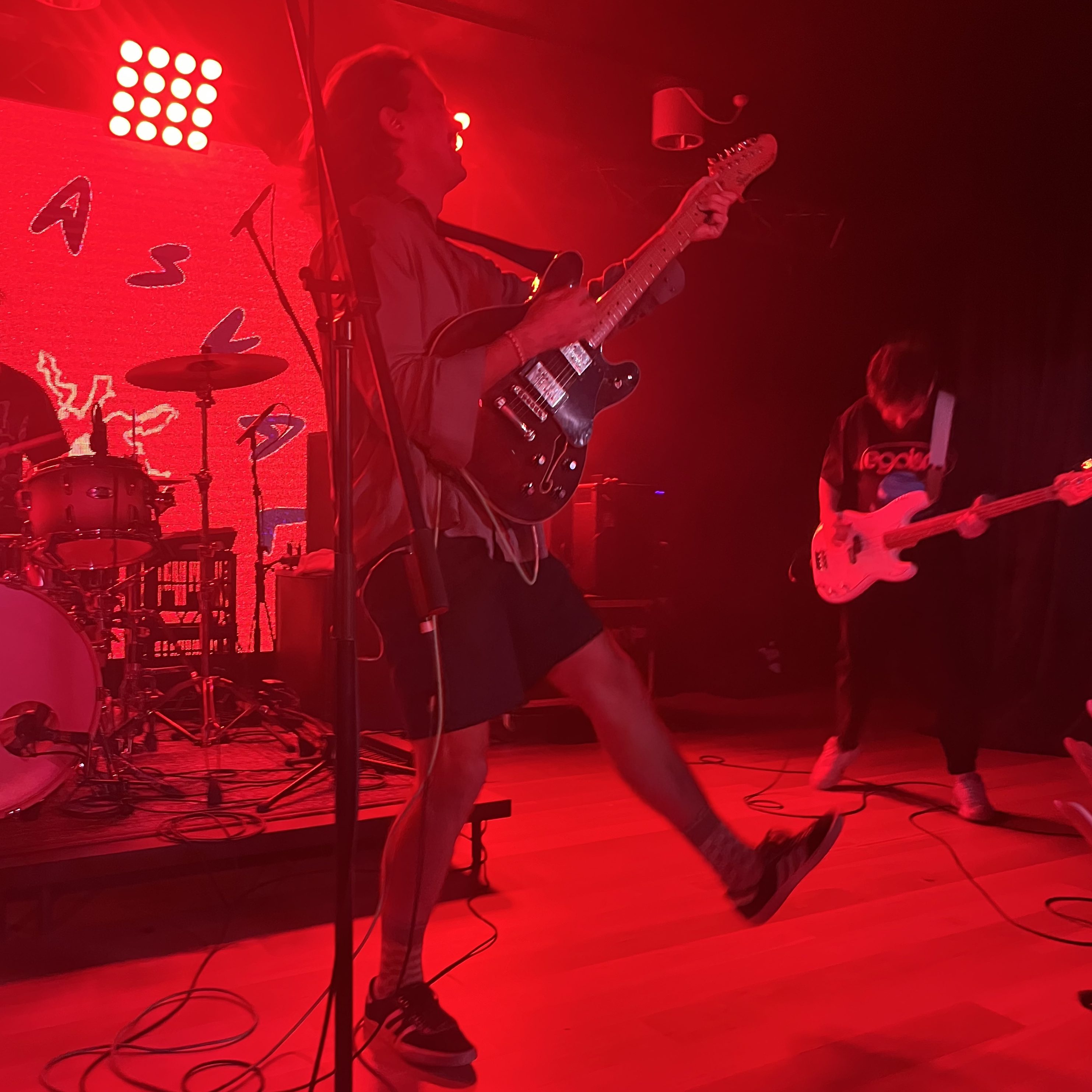 Man plays guitar with one leg in the air.