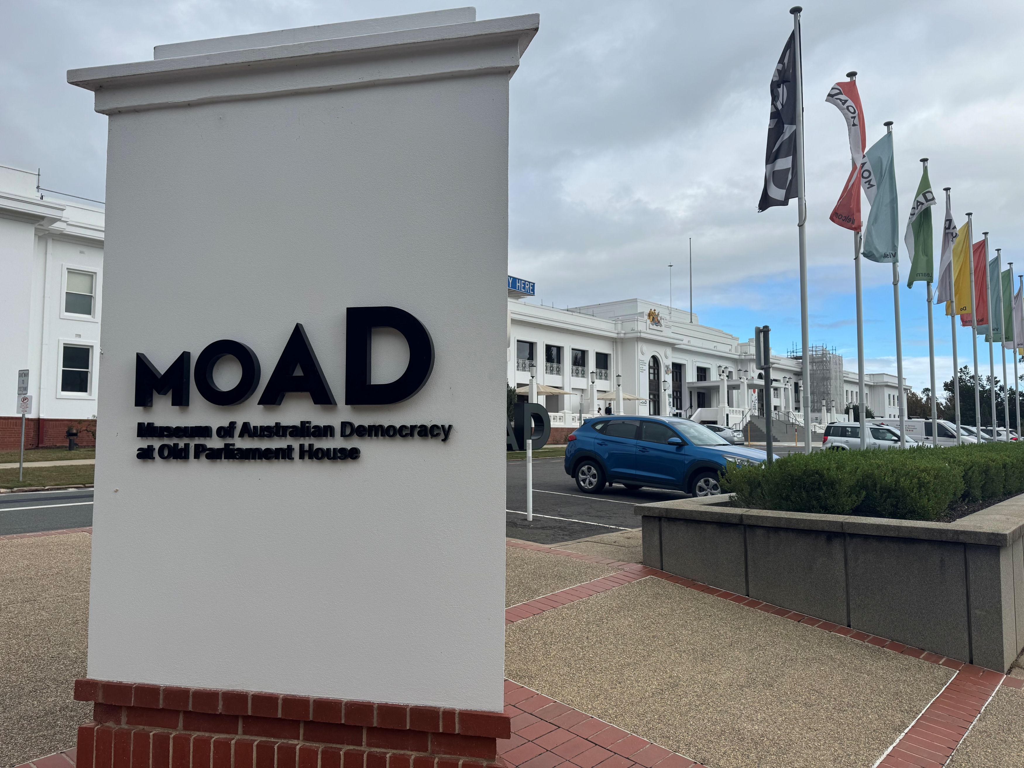 The outside of Old Parliament House with the main sign in foreground reading MOAD, Museum of Australian Democracy