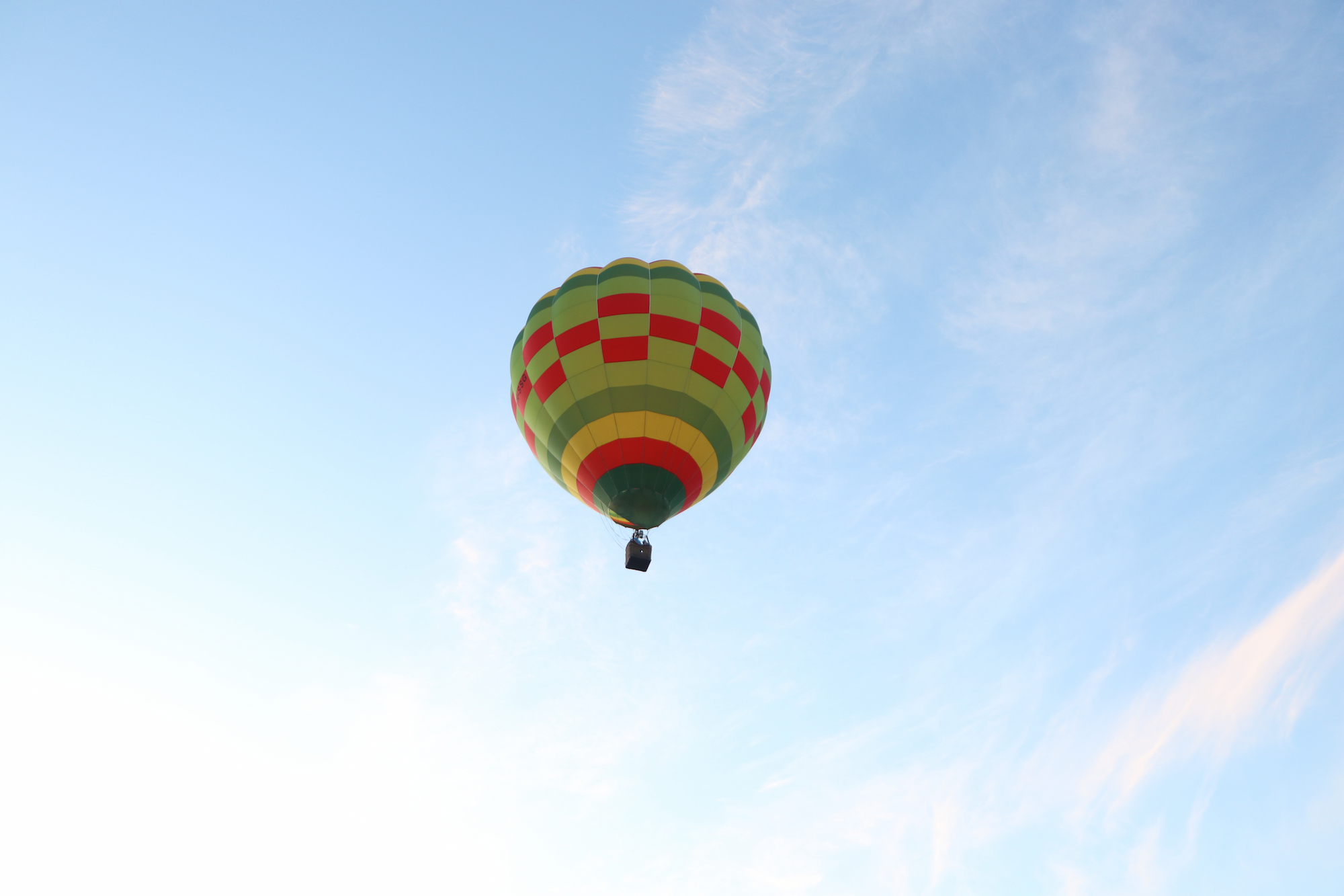 Colourful hot air balloon with a checkerboard pattern floating in a blue sky.