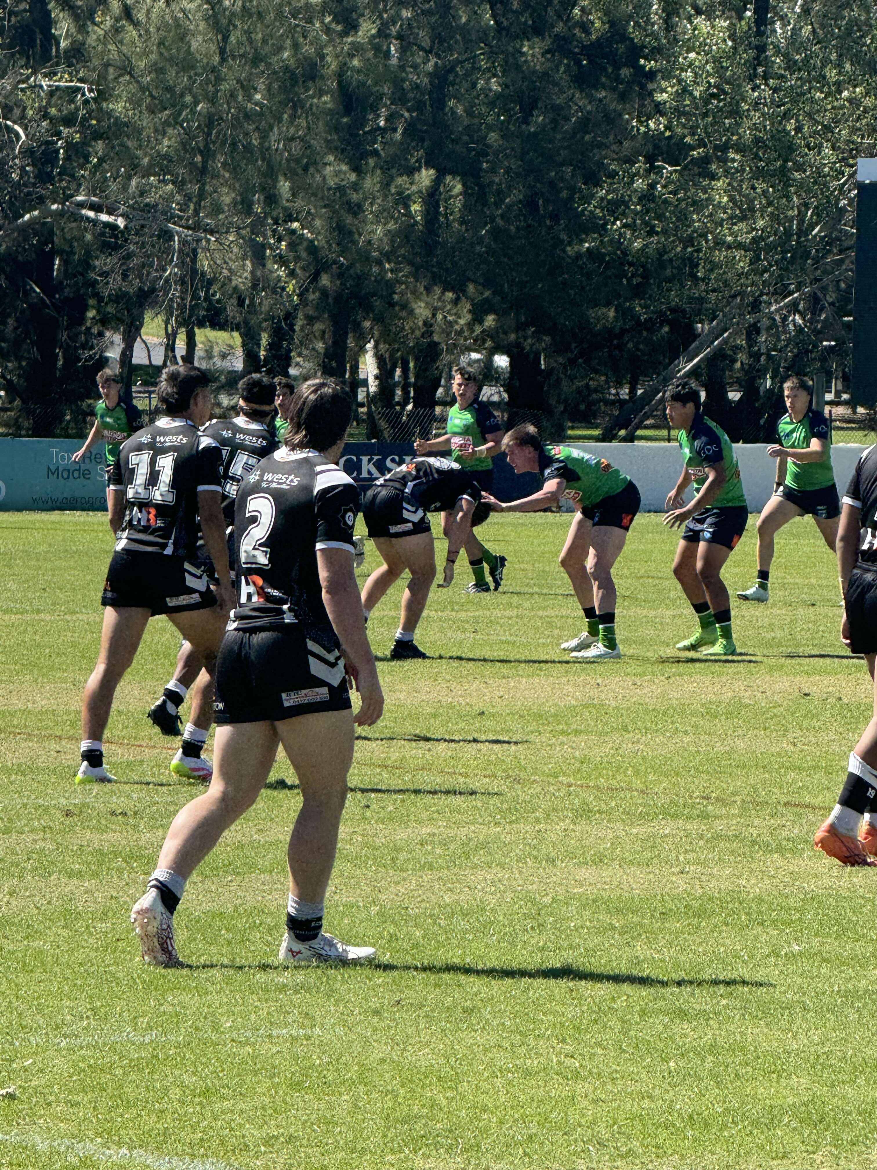 Magpies playing the ball with Raiders defending.