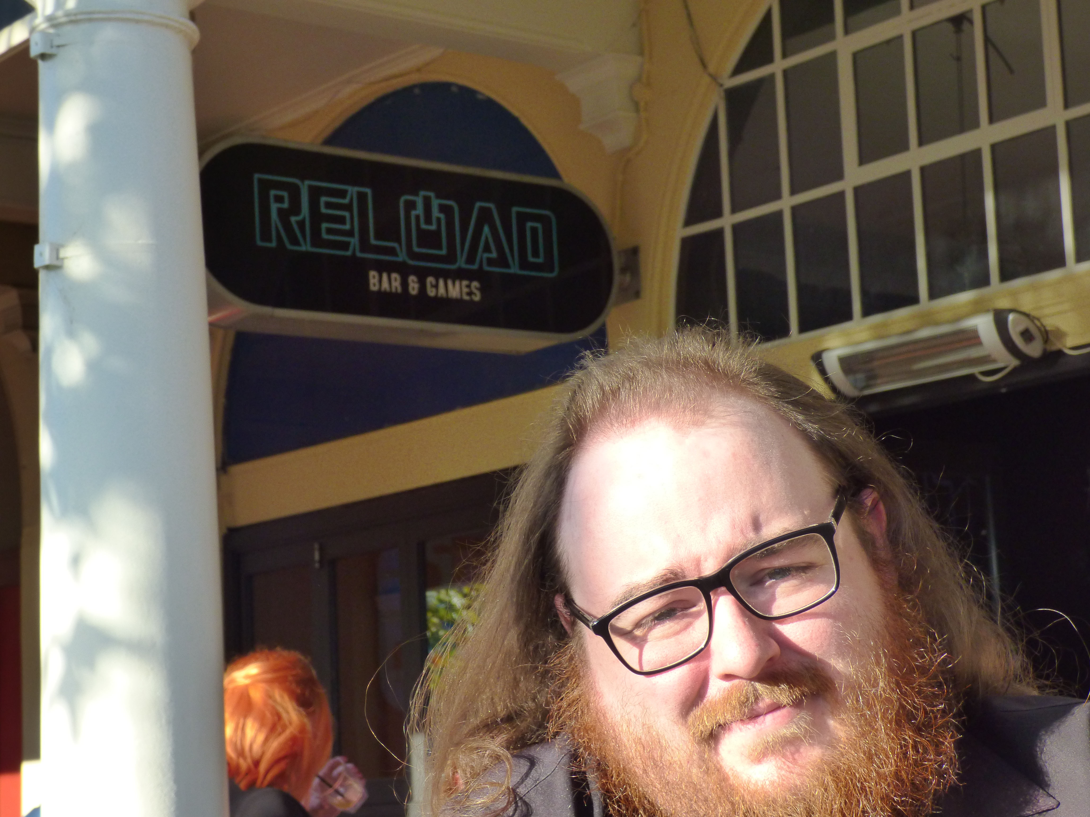 Headshot of a Reload Patron - with the main Reload Bar sign behind him.