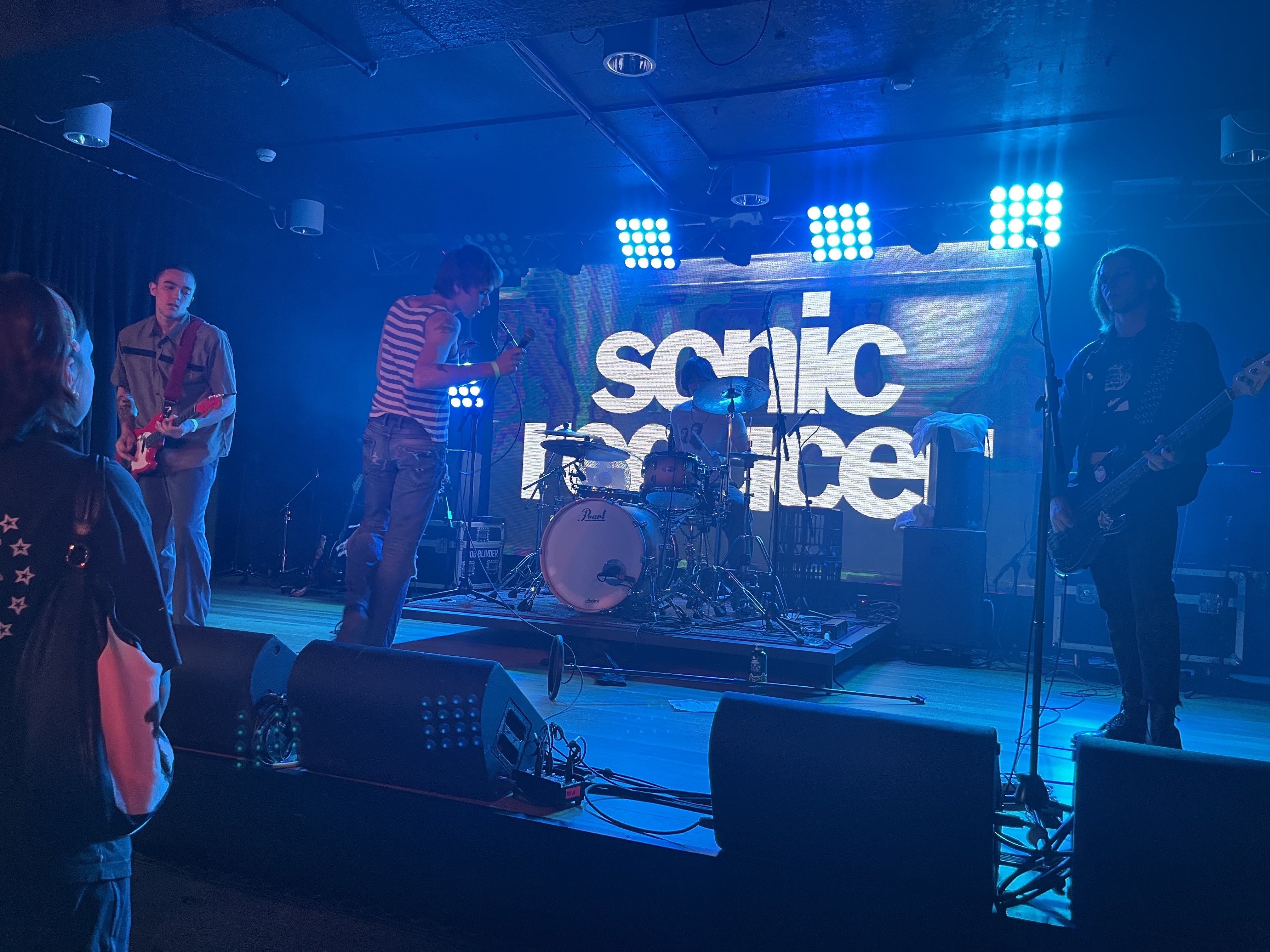 Rock band on a raised stage playing for an audience.