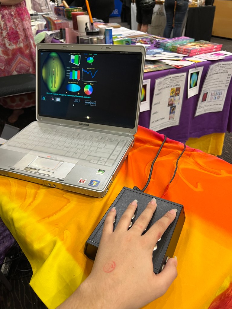 Hand on sensor with laptop in background showing aura data
