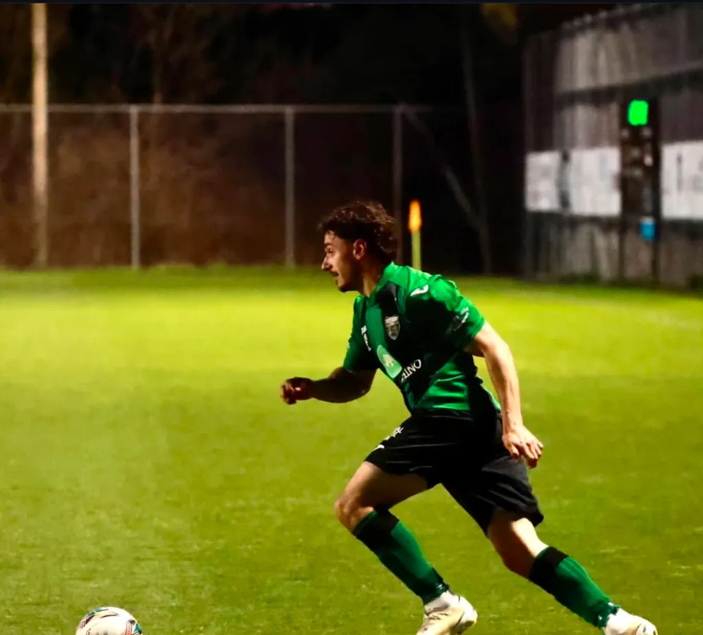man in green football kit running mid soccer game