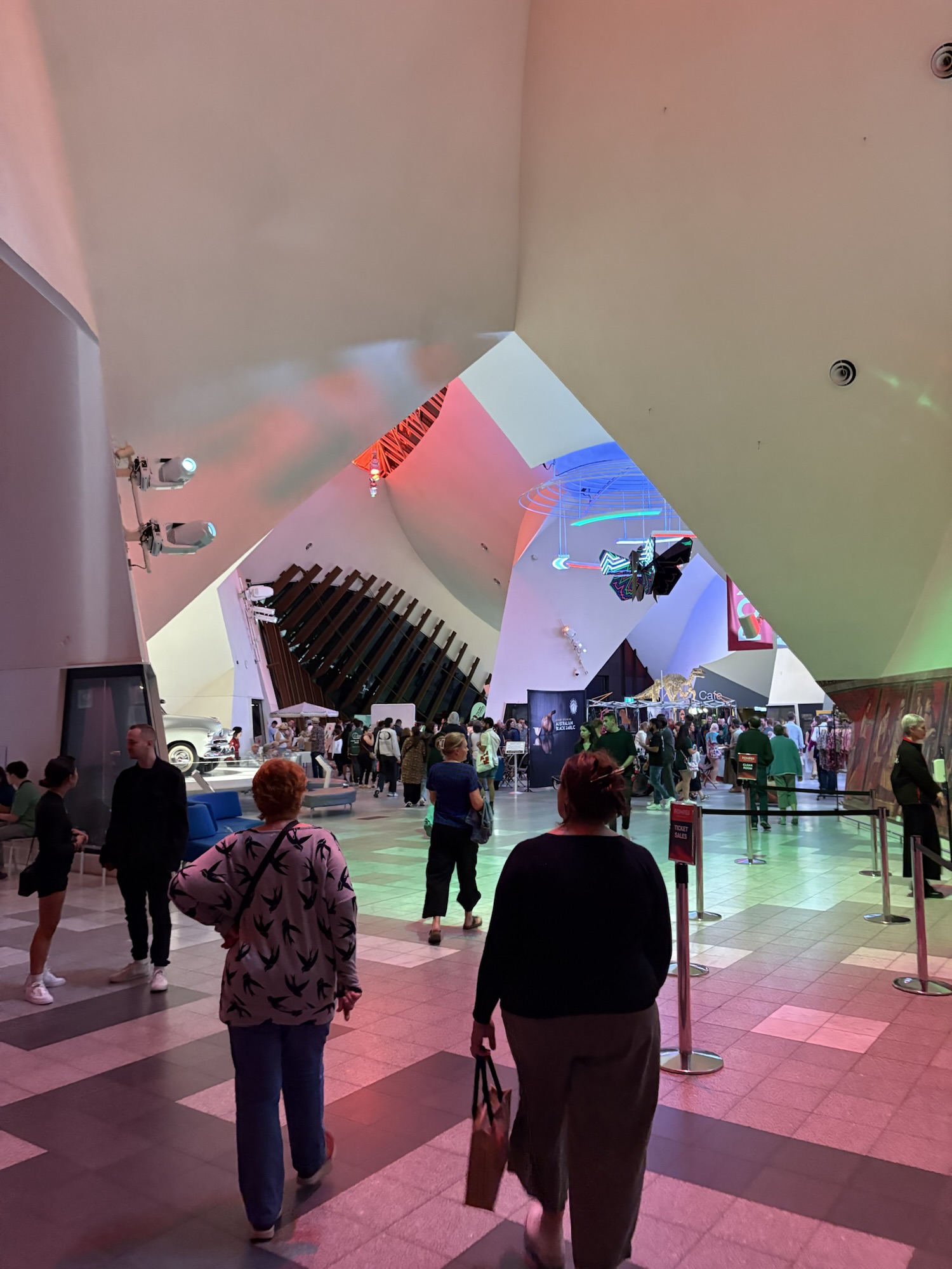 Photograph inside the National Museum of Australia, showing a large crowd and market stalls in the background