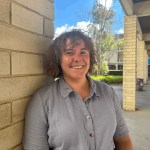 Isabel Mudford smiling, whilst leaning against pillar.