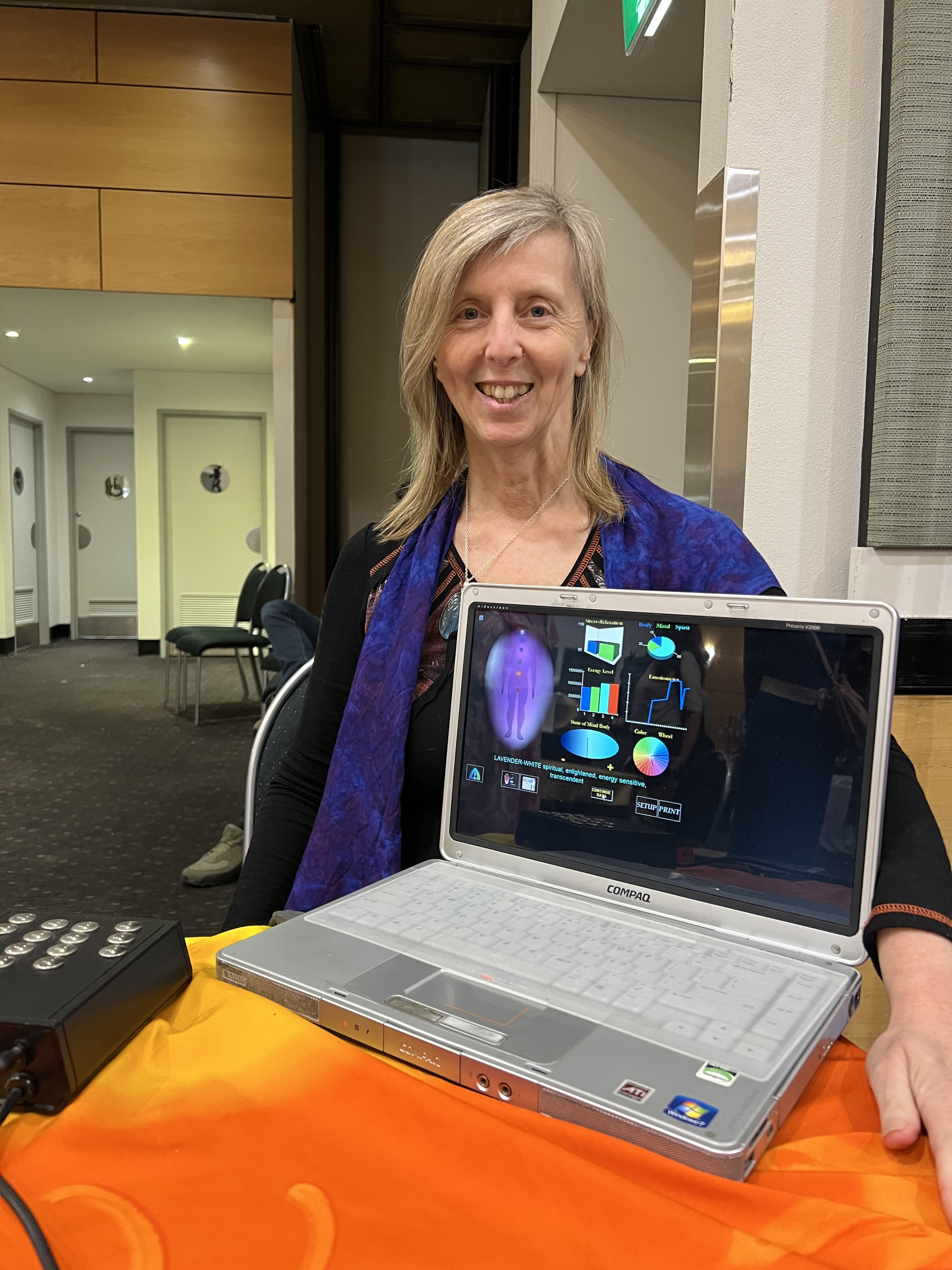Woman smiling behind laptop showing data about aura and chakras