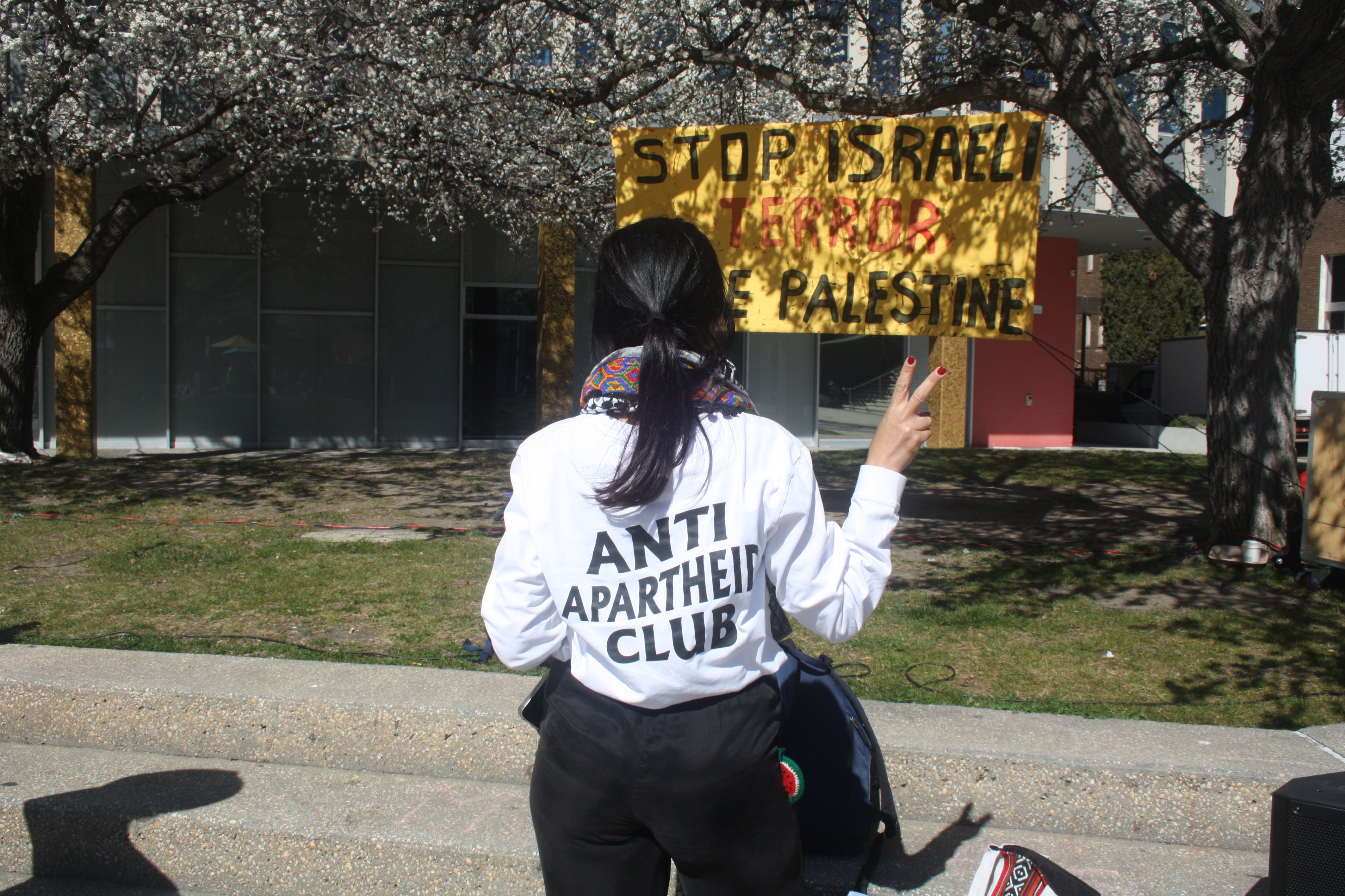 A member of the Palestine Action Group wearing a shirt that says "Anti Apartheid Club".