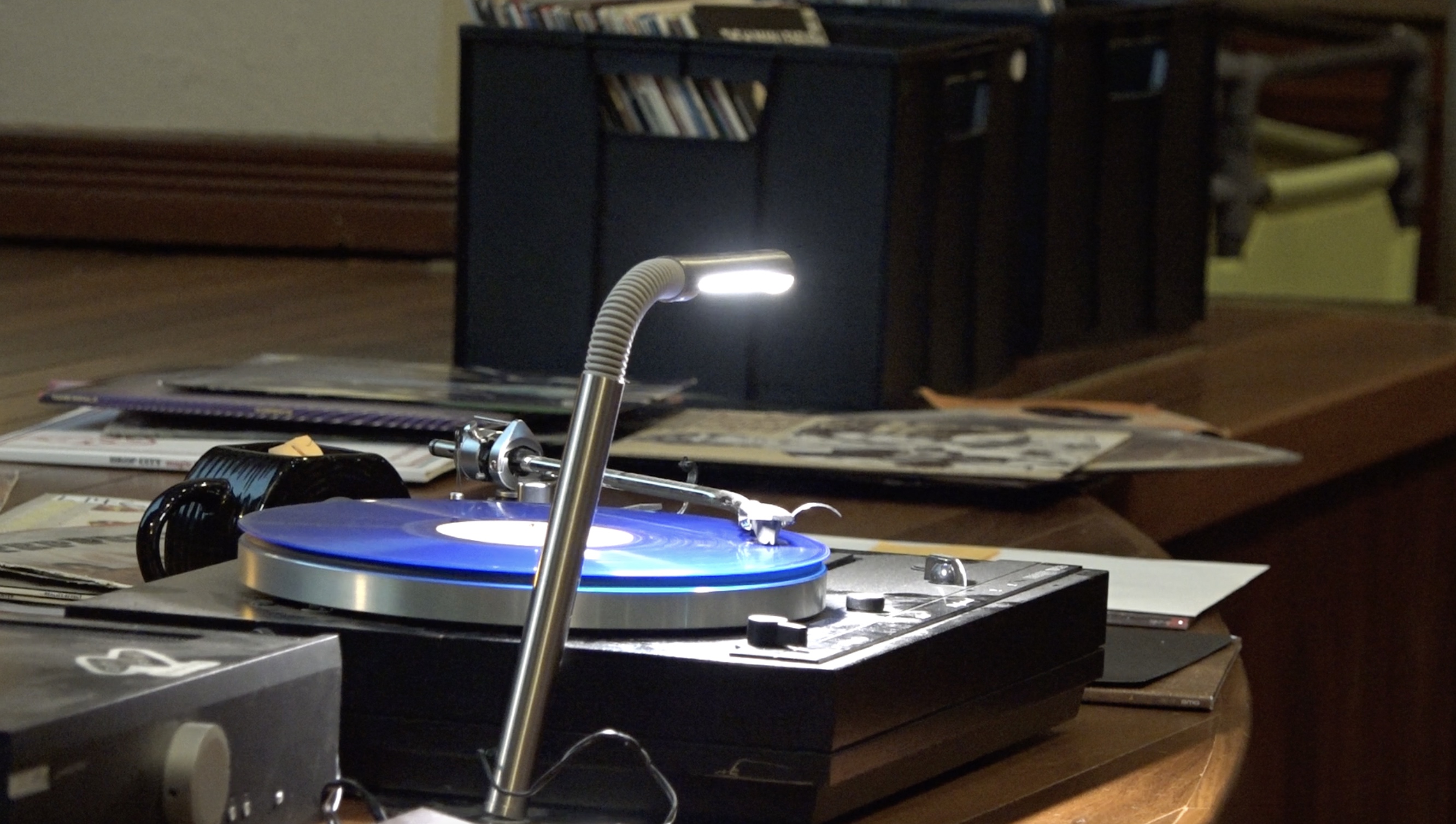 A bright blue vinyl spins on a black record player