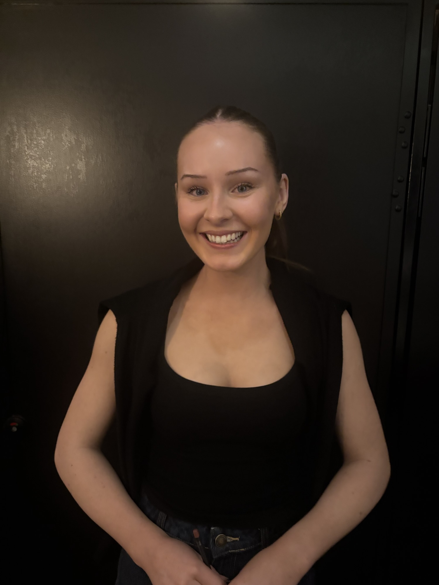Photograph of a girl smiling against a black background 