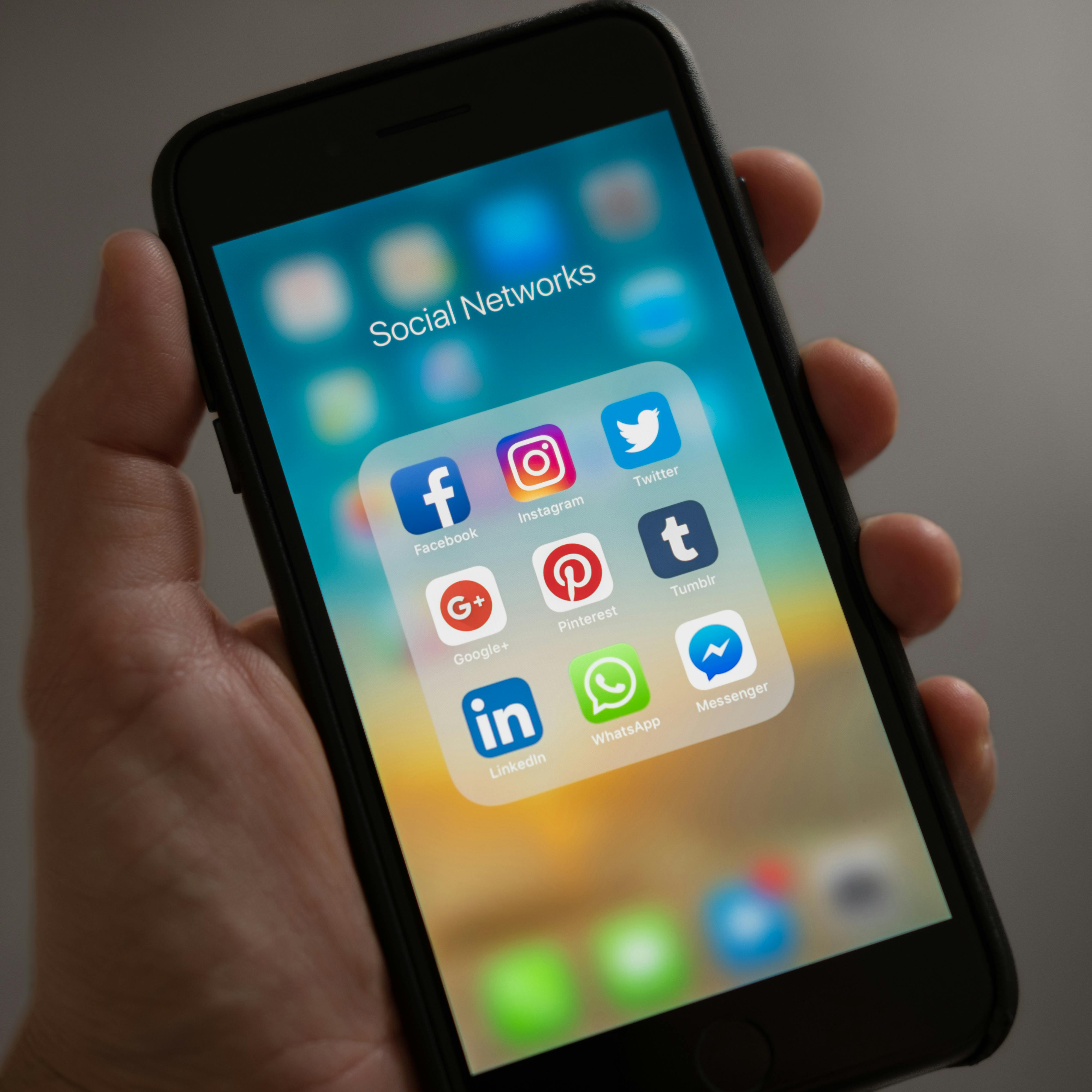 Someone holding a phone with social media apps on screen.