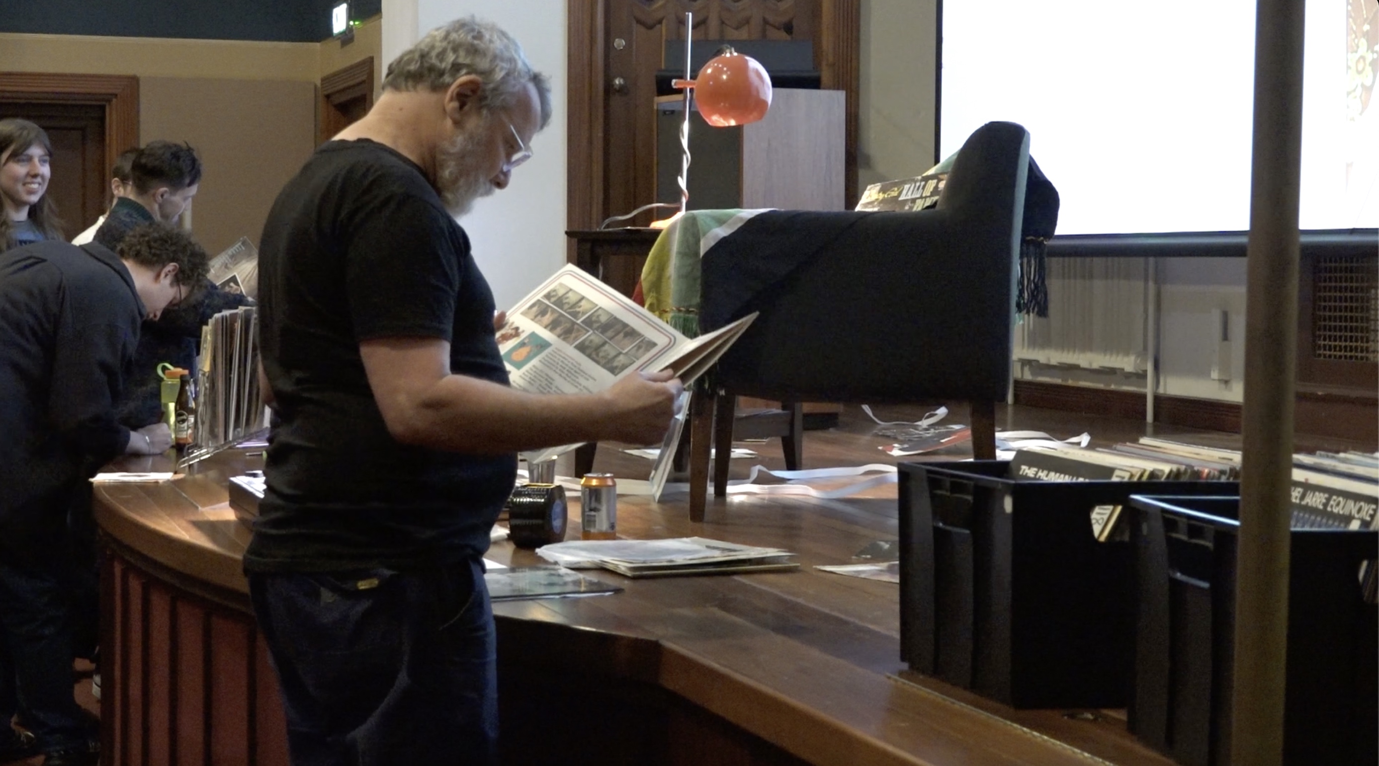 Thorsten stands looking at a vinyl. On the stage in front of him is an armchair and crates of records.