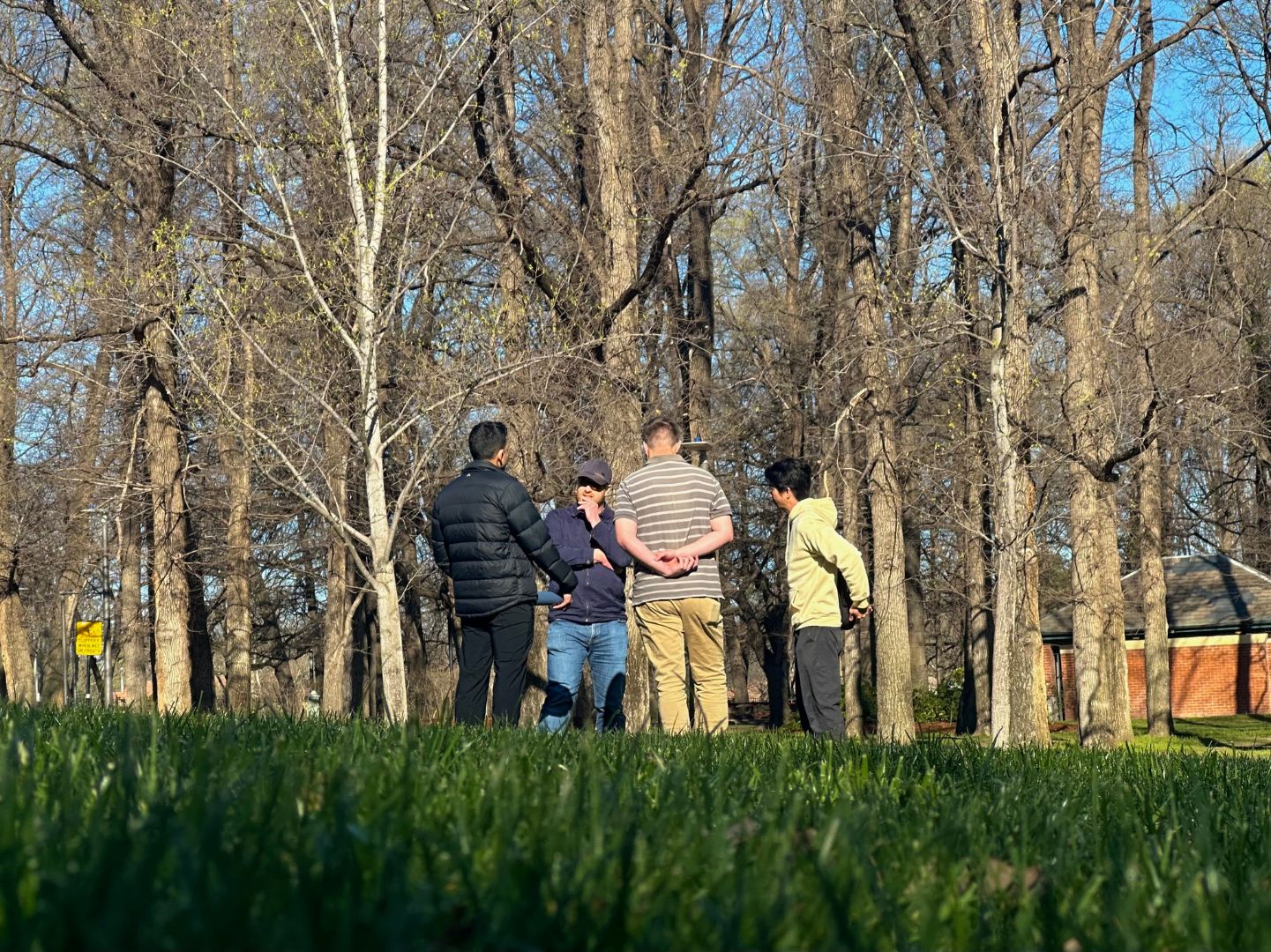 Group of four men talking in a circle in Glebe Park. 