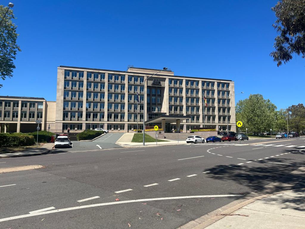 Large multistory building towers over a busy road.