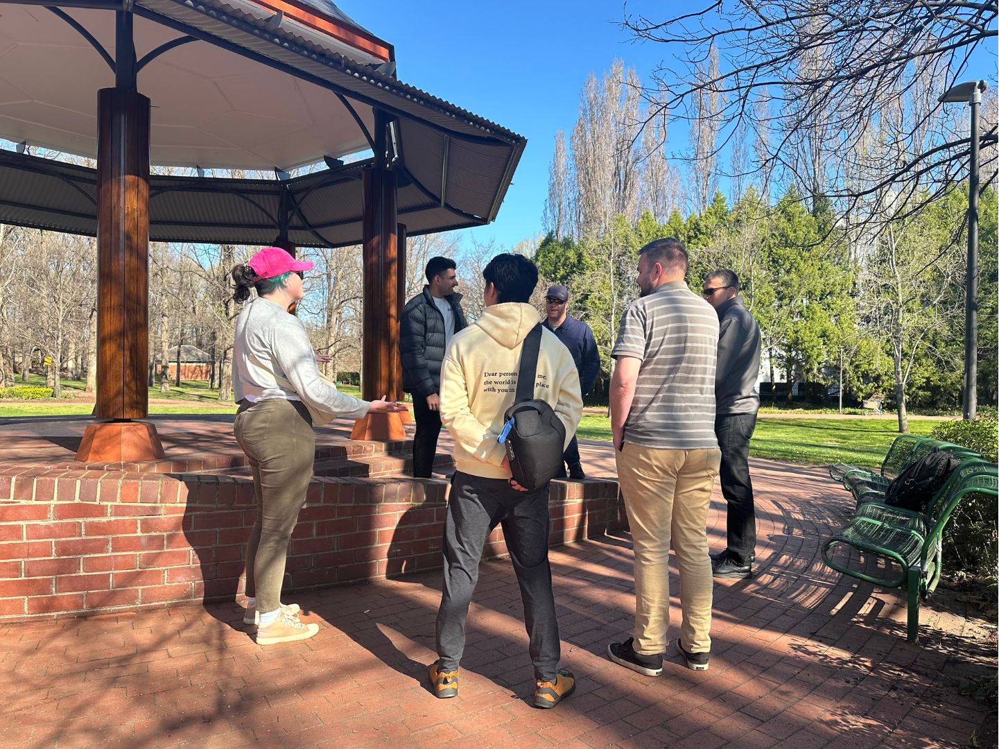 Group of six people standing in a circle near a gazebo.