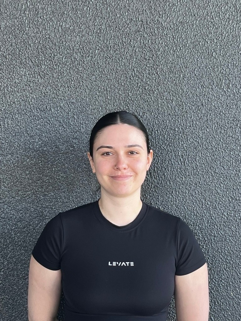 girl smiling infront of a blank concrete wall 
