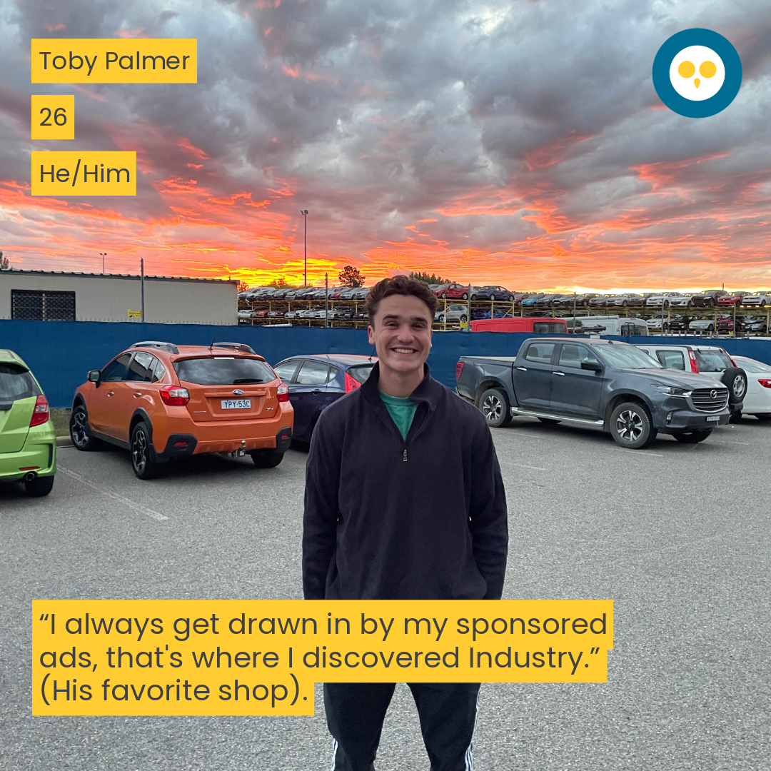 man standing in a carpark infront of a sunset smiling 