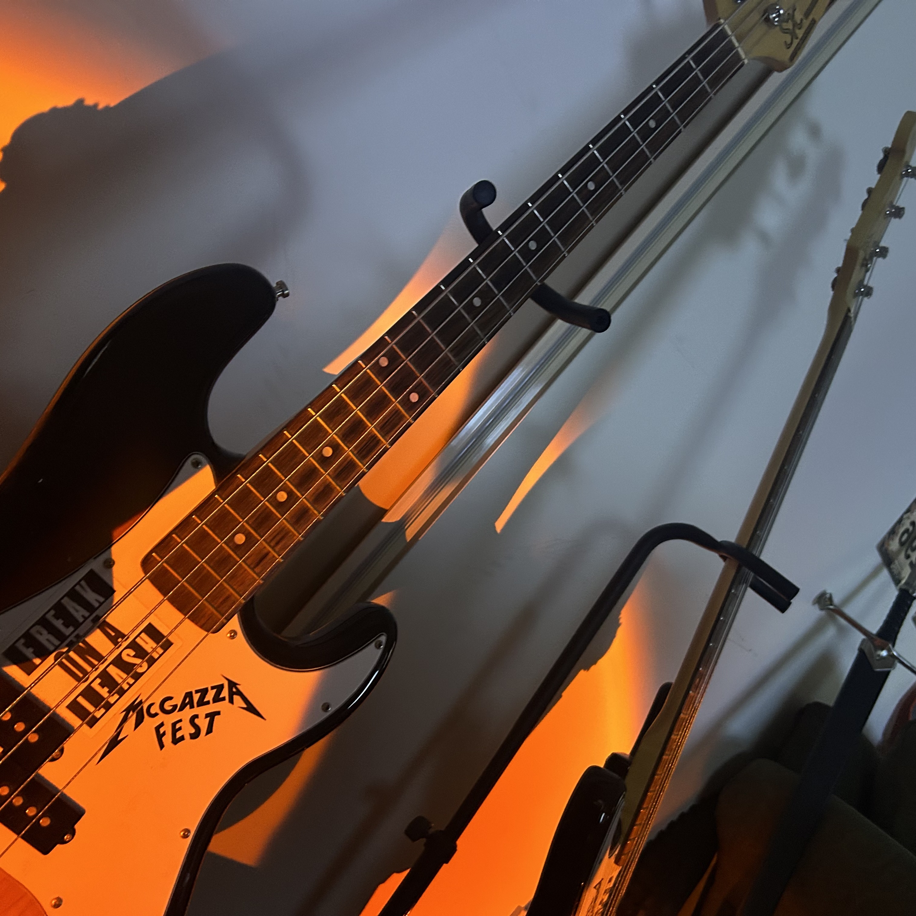 A bass guitar in a stand with a warm orange glow