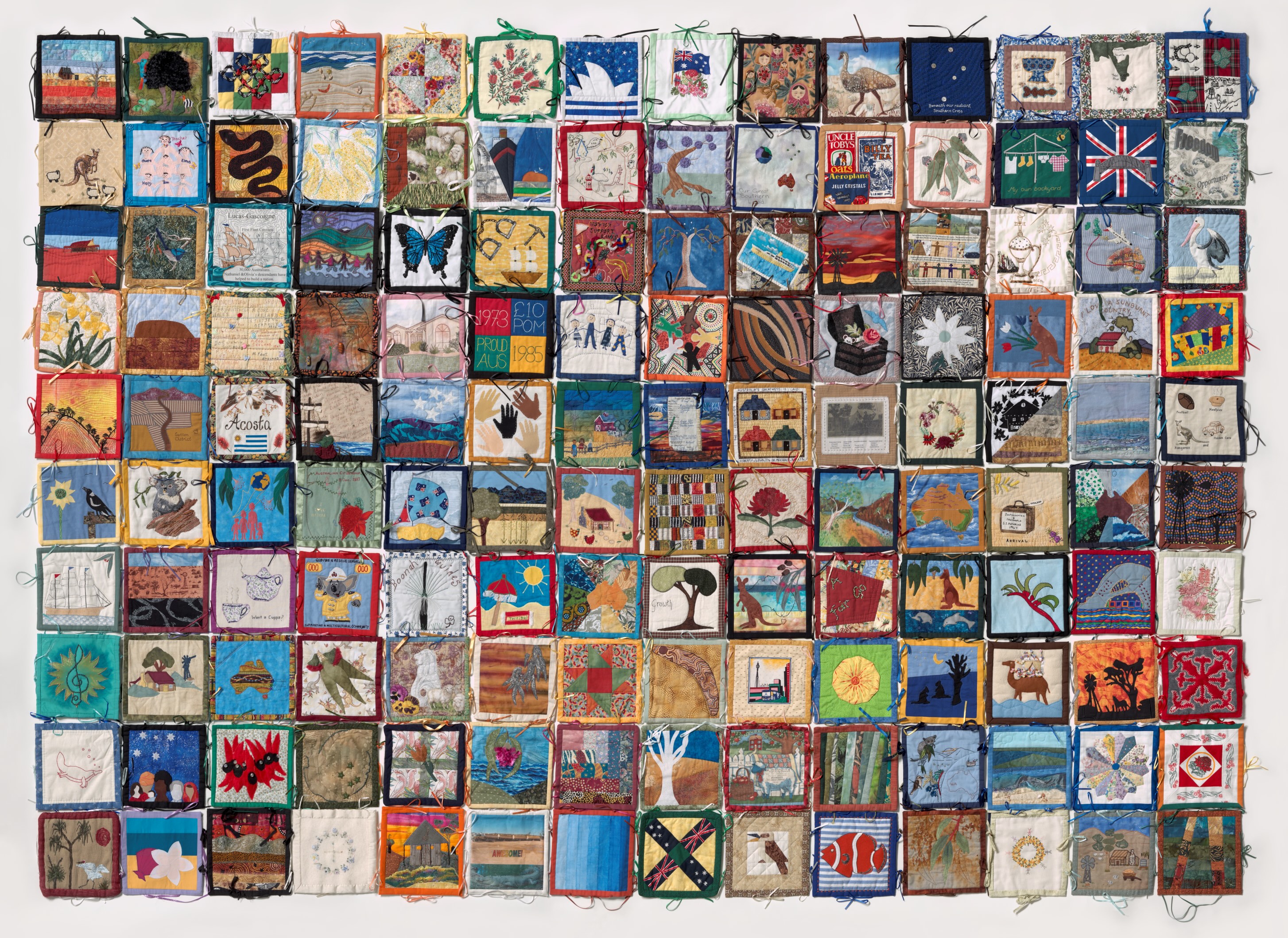The Australian Citizenship Quilt. A large quilt with a variety of designs on each square. The squares have been tied together with ribbon.