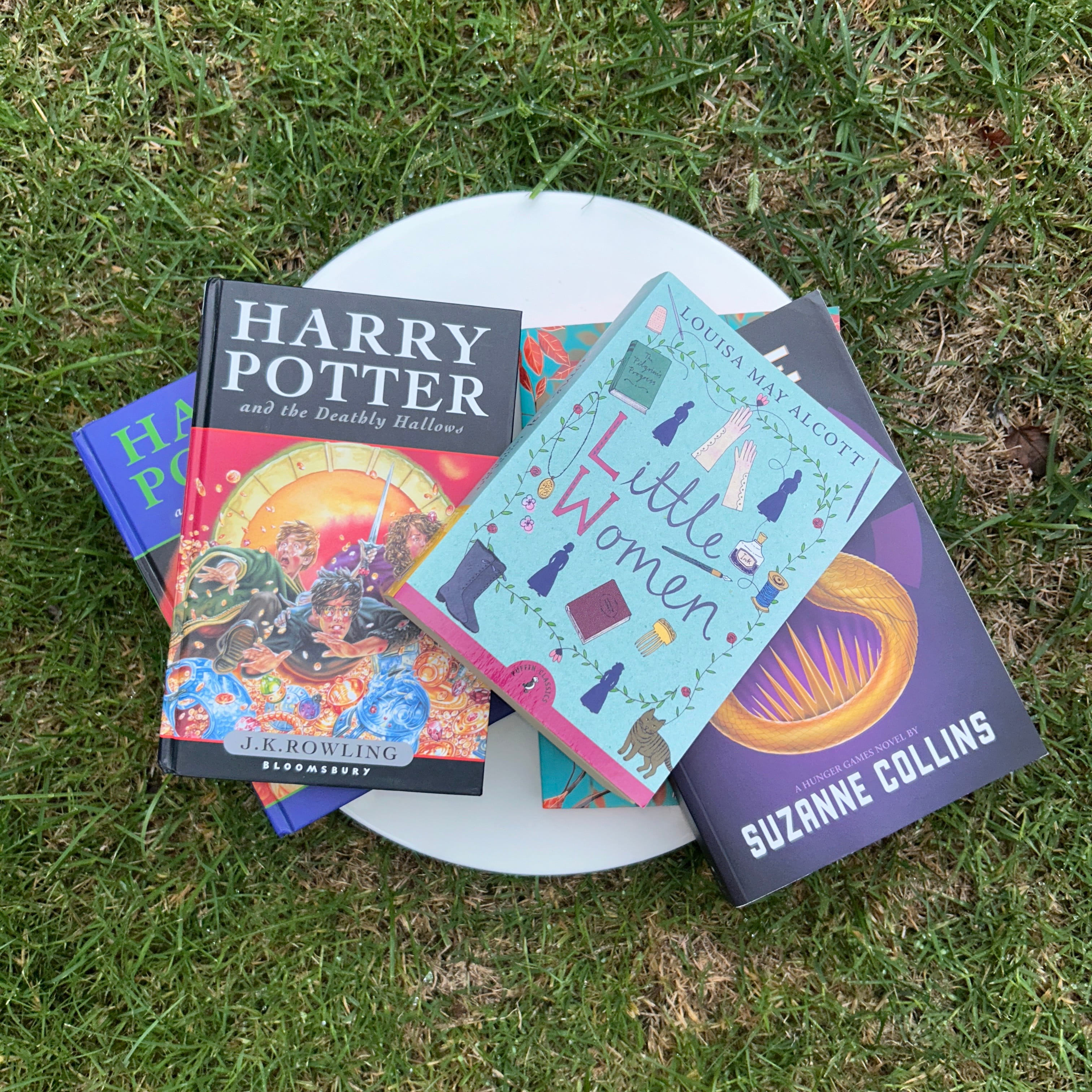 A pile of overlapping books laying on grass.