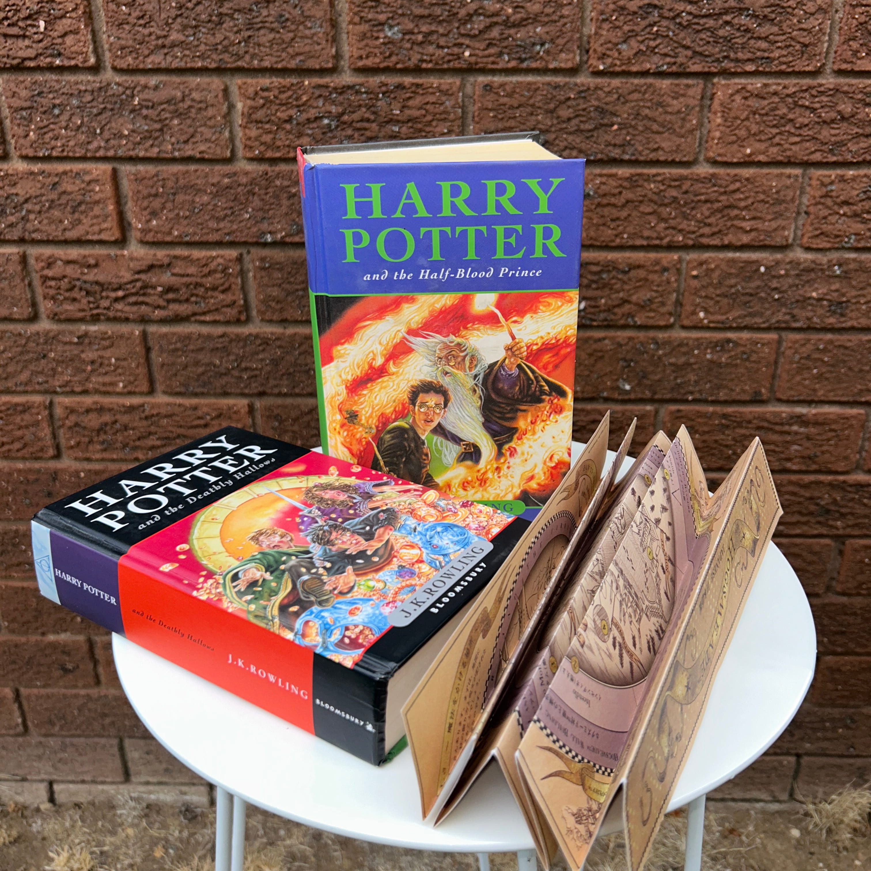 Two Harry Potter books and a stylised map sitting in front of a brick wall.