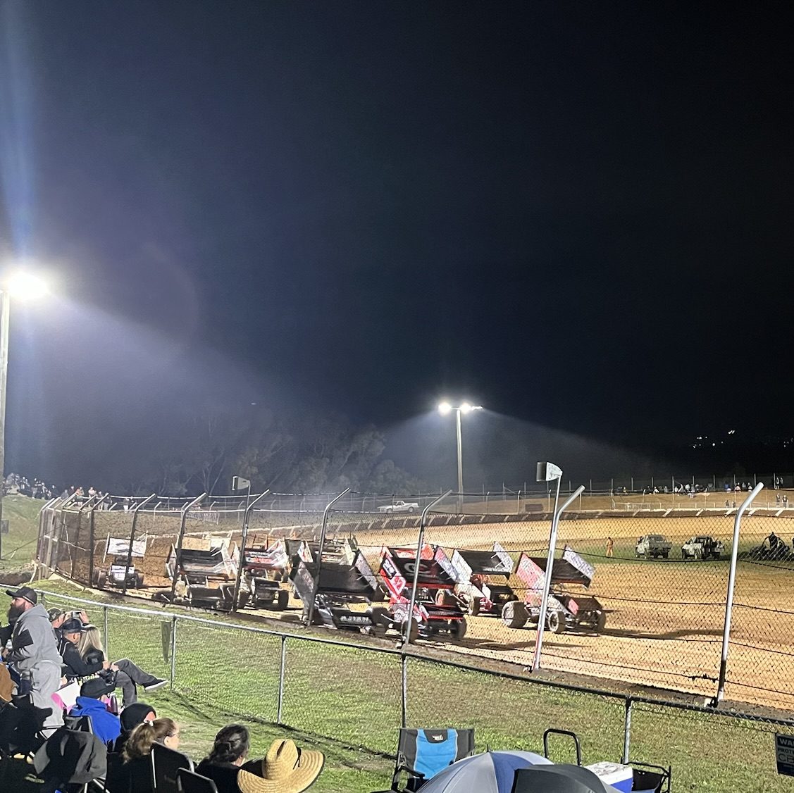 The start of the feature race with many sprint cars grouped together on the track.