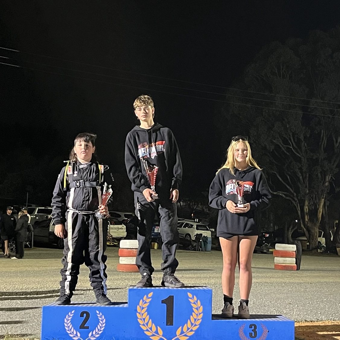 The Junior Sedans podium with each winning driver holding a cone-shaped trophy.