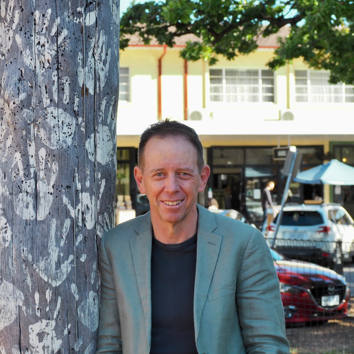 Shane Rattenbury leaning against a tree and smiling