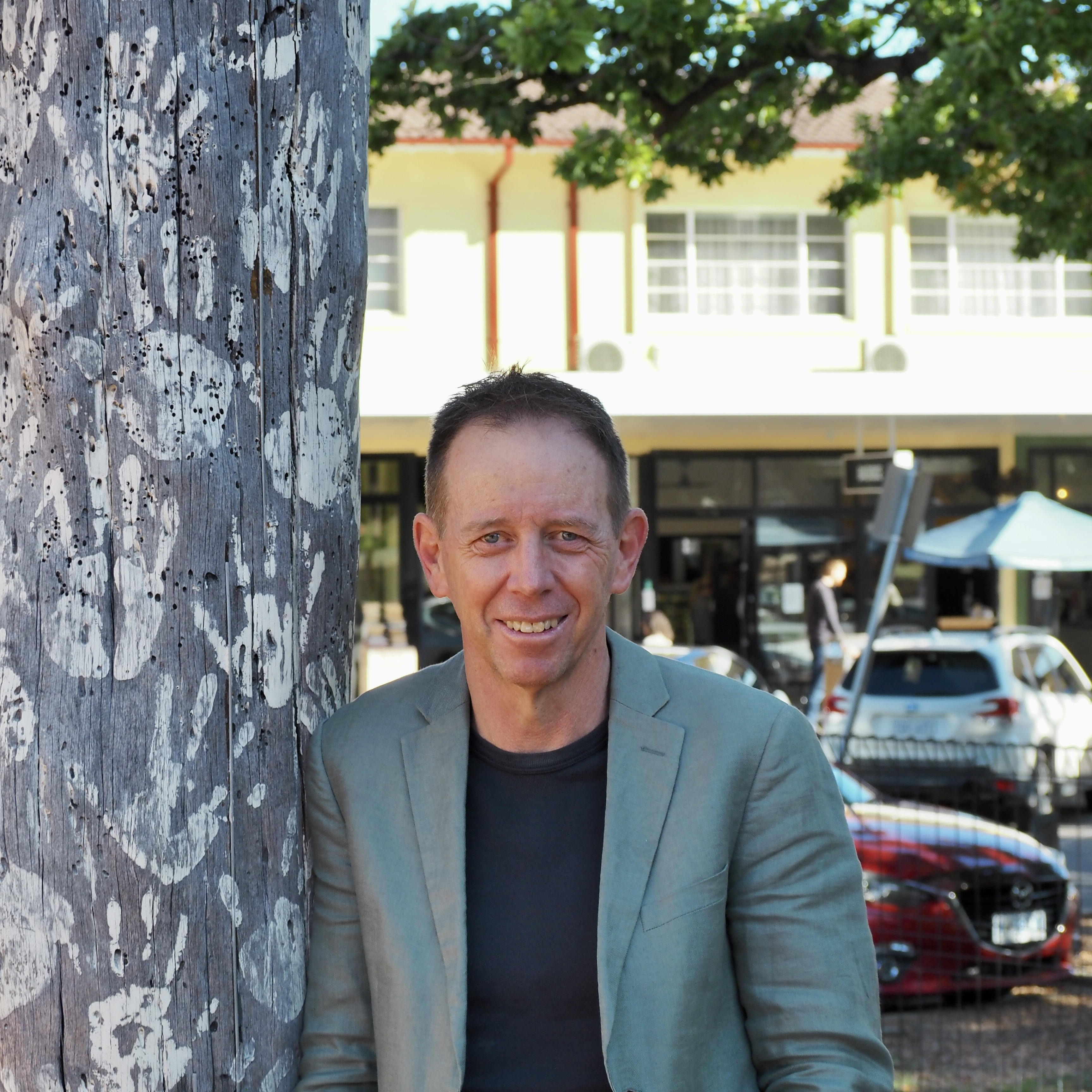 Shane Rattenbury leaning against a tree and smiling.