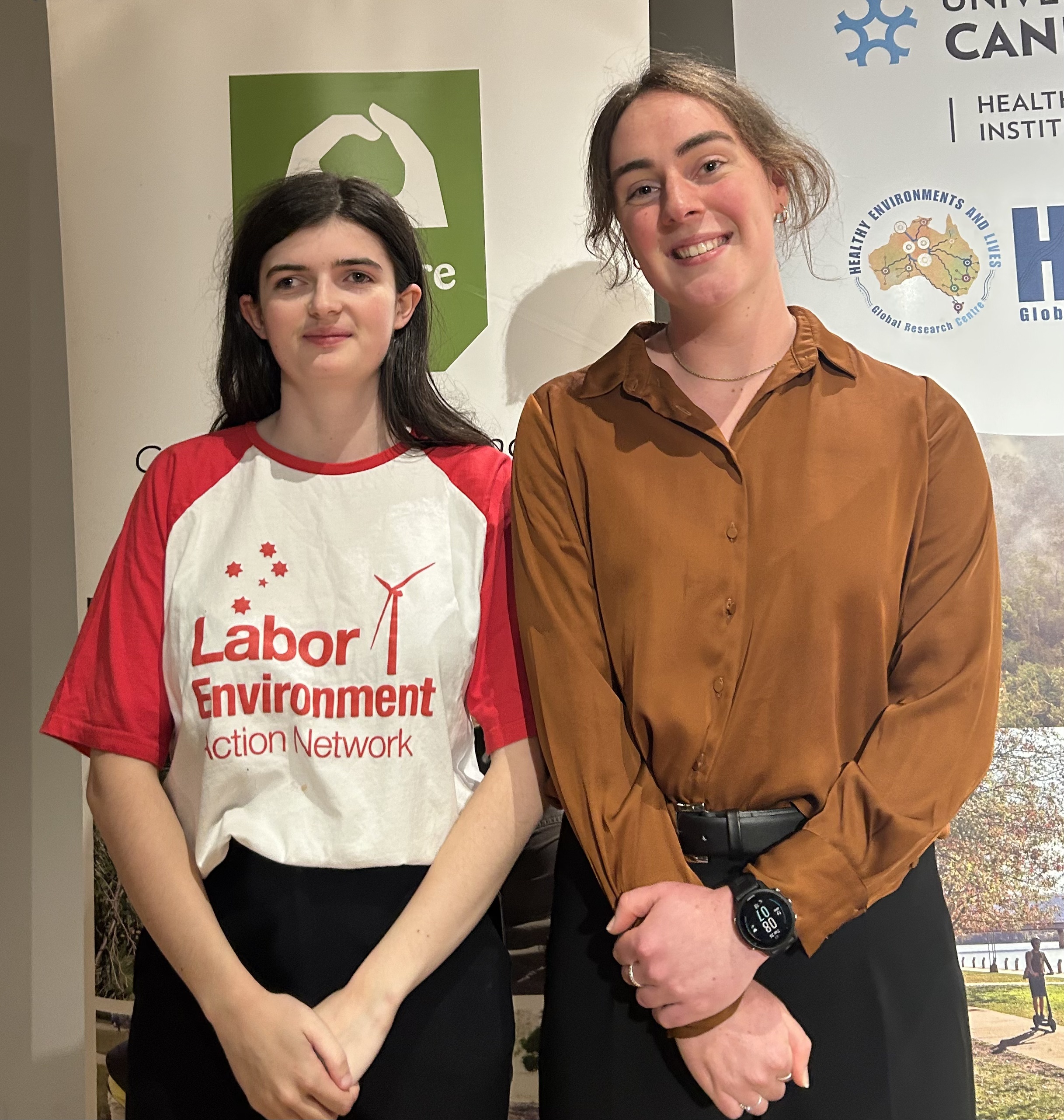 Young activists and event panelists Lucinda Adams and Hannah Vardy standing in front of Landcare ACT sign.